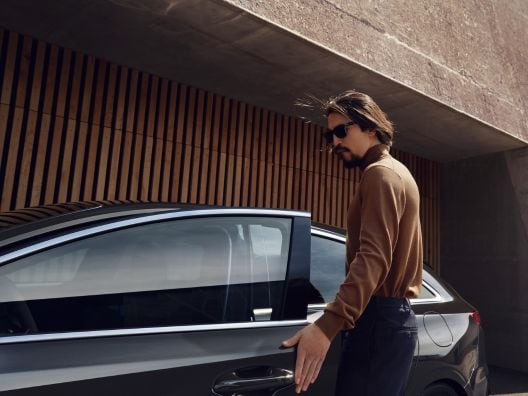 Osoba wsiadająca do czarnego samochodu.